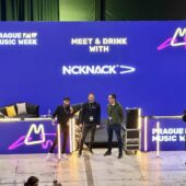 1. Neonové logo prague music week a skupiny NICKNACK na velké scéně s three hosty a fotografy, moderní koncertní prostředí, živé osvětlení, večerní atmosféra.